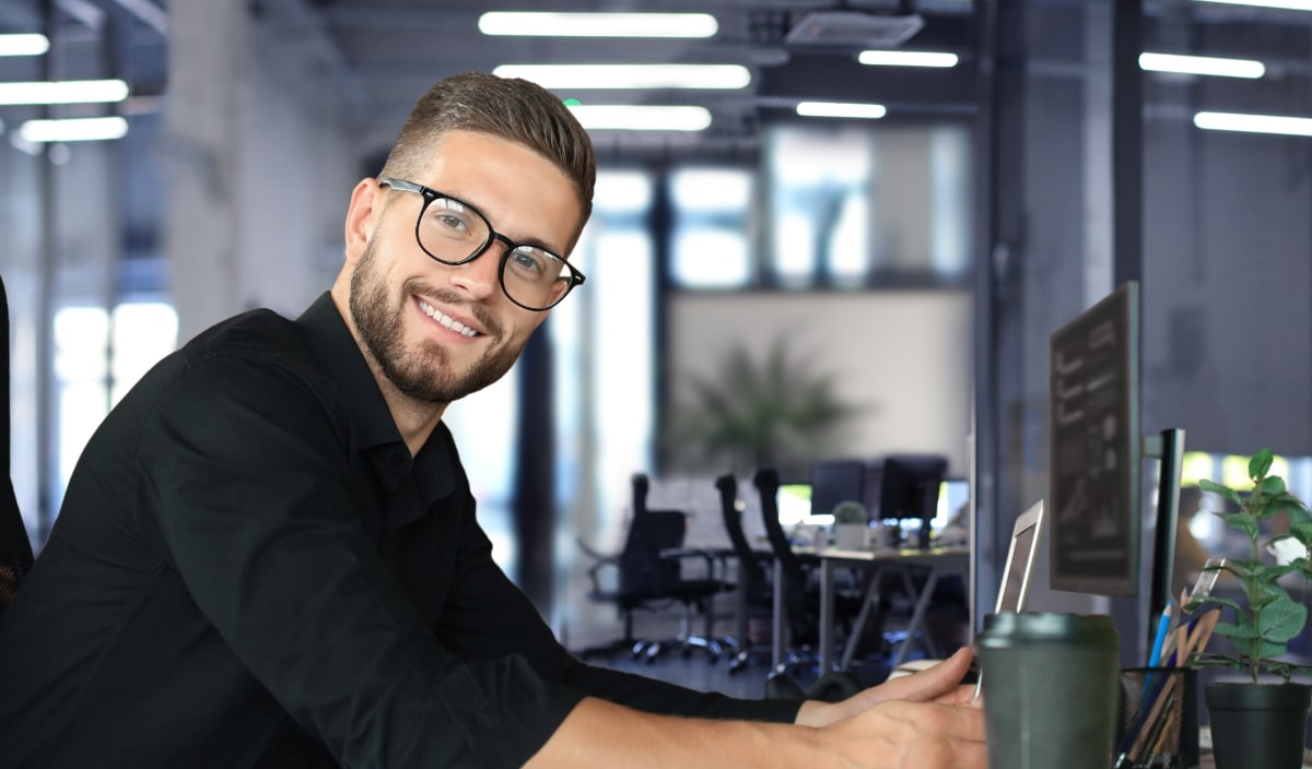 Young man with beard and glasses at desk